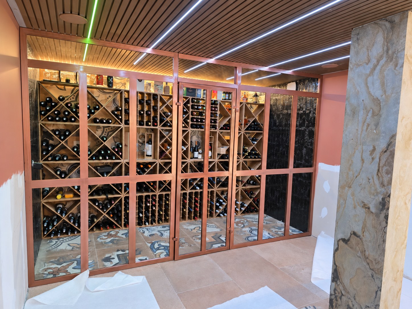 Verrière sur mesure fermée, laquage aspect cuivre brossé, devant une cave à vin entre Loire et Haute-Loire